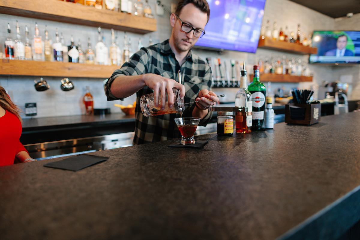 Bartender pouring a cocktail at the Scissors & Scotch bar