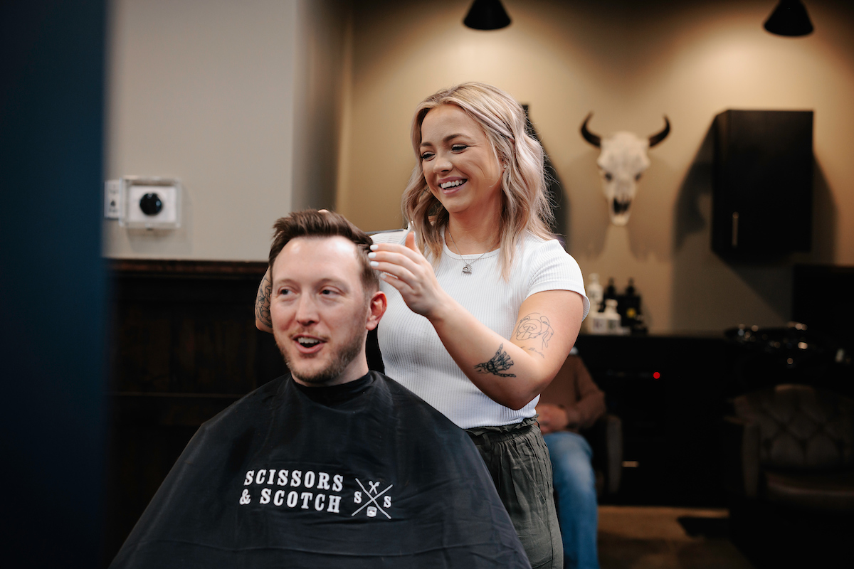 Stylist giving a precision haircut in a Scissors & Scotch cape